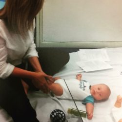 A photo of Cara massaging baby Everett's legs during a practice infant massage session at physical therapy