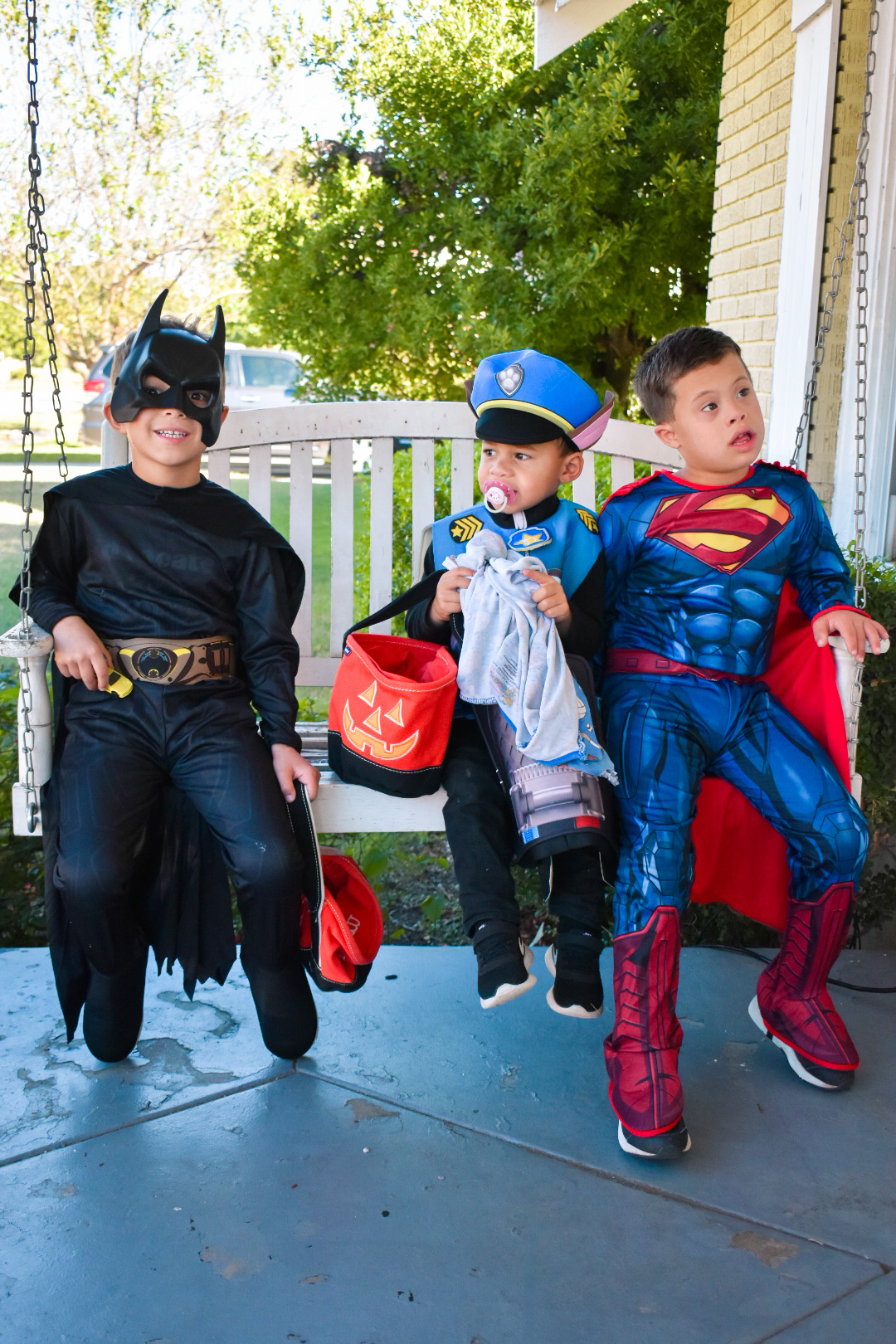 Three little boys dressed up as Chase from Paw Patrol, Superman, and Batman for halloween