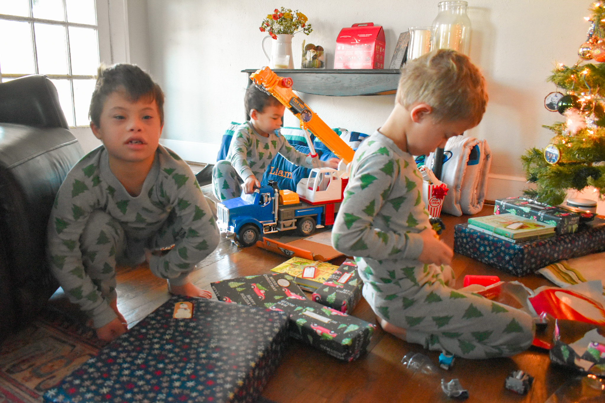 Three little boys opening up presents by the tree